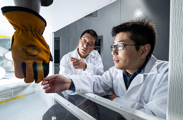 Guowen Song and Rui Li examining a glove in a lab